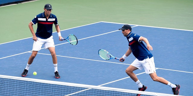 Mike Bryan, left, returns a shot as his brother Bob Bryan, looks on during a first round doubles match against Hubert Hurkacz, of Poland, and Vasek Pospisil, of Canada, at the US Open tennis championships Friday, Aug. 30, 2019, in New York.