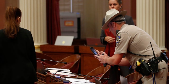 A California Highway Patrol Officer photographs a desk on the Senate floor after a red liquid was thrown from the Senate Gallery during the Senate session at the Capitol in Sacramento, Calif., Friday, Sept. 13, 2019. (Associated Press)