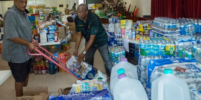 Ryan Smith, 60, left, and Hiram Williams, 71, stocking an auditorium with goods slated to be sent to the Bahamas at Christ Episcopal Church in Miami on Tuesday. (AP Photo/Ellis Rua)