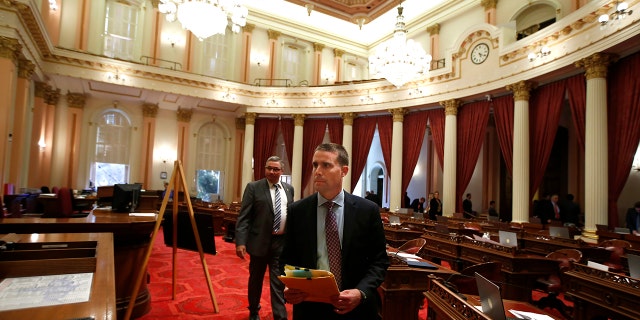 State Senator Mike McGuire, D-Healdsburg, right, leaves the Senate Chambers after a red substance was thrown from the Senate Gallery during the Senate session at the Capitol in Sacramento, Calif., Friday, Sept. 13, 2019. (AP Photo/Rich Pedroncelli)