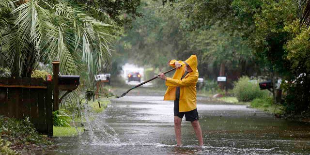 An Isle of Palms resident clears the drain on Hartnett Blvd. during Hurricane Dorian at the Isle of Palms, S.C., Thursday, Sept. 5, 2019, in Charleston, S.C. (AP Photo/Mic Smith)