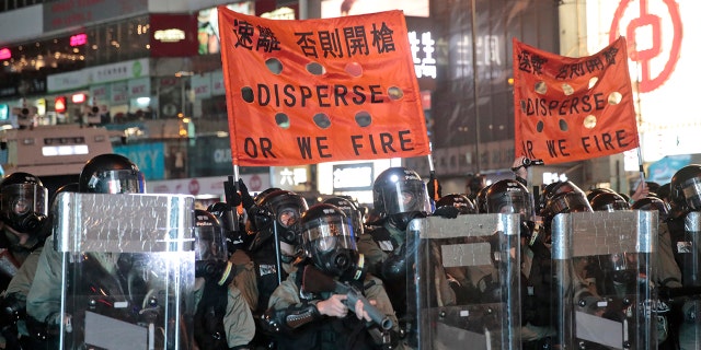 Police officers hold banners ordering protestors to disperse. Protesters made a wall out of barricades and set it afire. (AP Photo/Jae C. Hong)