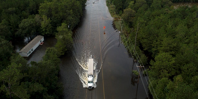 A truck drives through a flooded highway as flooding from the remnants of Tropical Storm Imelda continues in Southeast Texas on Friday, Sept. 20, 2019, in Mauriceville, Texas. (Jon Shapley/Houston Chronicle via AP)