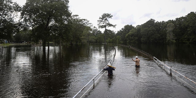 Mike Davis, left, and Trent Tipton, the two workers in Woodville, Texas, cross the floodwaters to try to restore power to a customer on Friday, Sept. 20, 2019 in the area of ​​Mauriceville, Texas. The floodwaters are beginning to retreat into most of the Houston area after flooding remnants of tropical storm Imelda in parts of Texas. (Jon Shapley / Houston Chronicle via AP)