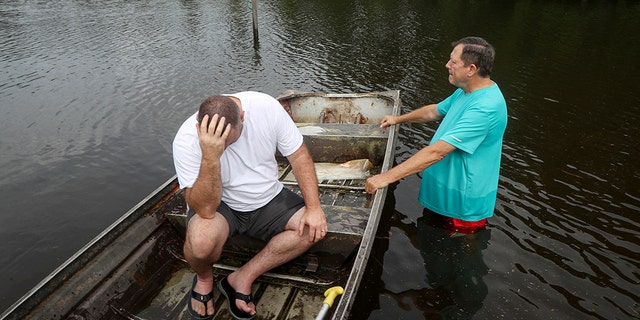 Stephen Gilbert, left, and his father-in-law sit in front of their flooded property on Friday, Sept. 20, 2019, in the Mauriceville, Texas, area. Floodwaters are starting to recede in most of the Houston area after the remnants of Tropical Storm Imelda flooded parts of Texas. "I'm on my third house," said Gilbert, who lives behind his father-in-law. "I wouldn't go anywhere else in the world," he said. "All we have is family anyway." (Jon Shapley/Houston Chronicle via AP)