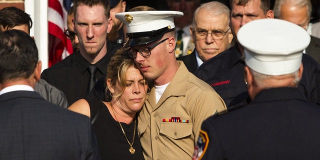Erika Starke, left, is comforted by her son Michael Haub as they attend a second funeral service for New York Fire Department firefighter Michael Haub, in Franklin Square, N.Y., Tuesday, Sept. 10, 2019. (AP Photo/Eduardo Munoz Alvarez)