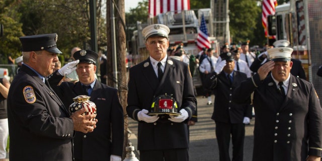 A New York Fire Department member, left, carries the remains of FDNY firefighter Michael Haub during second funeral service for him in Franklin Square, N.Y., Tuesday, Sept. 10, 2019. (AP Photo/Eduardo Munoz Alvarez)