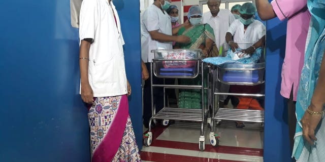 Hospital staff watch as proud dad Rajarao Mangayamma brings his new born twins to a press conference in India.