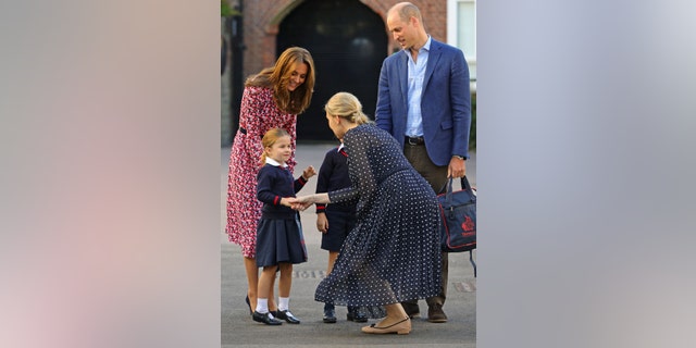 Britain's Princess Charlotte of Cambridge, accompanied by her father, Britain's Prince William, Duke of Cambridge, her mother, Britain's Catherine, Duchess of Cambridge, is greeted by Helen Haslem, head of the lower school on her arrival for her first day of school at Thomas's Battersea in London on Sept. 5, 2019.
