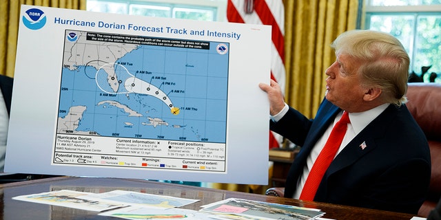 President Donald Trump is holding a painting as he talks with reporters after receiving a briefing on Hurricane Dorian at the White House Oval Office on Wednesday, September 4, 2019 in Washington. (AP Photo / Evan Vucci)