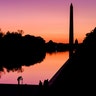 A photographer lines up her shot at the National Mall reflecting pool as the sun begins to rise behind the Washington Monument and the U.S. Capitol building in Washington, Sept. 21, 2019. 
