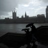 People are silhouetted with umbrellas in the rain backdropped by the Houses of Parliament in London, Sept. 24, 2019. 