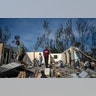 George Bolter and his parents walk through the remains of his home destroyed by Hurricane Dorian in the Pine Bay neighborhood of Freeport, Bahamas, Sept. 4, 2019.