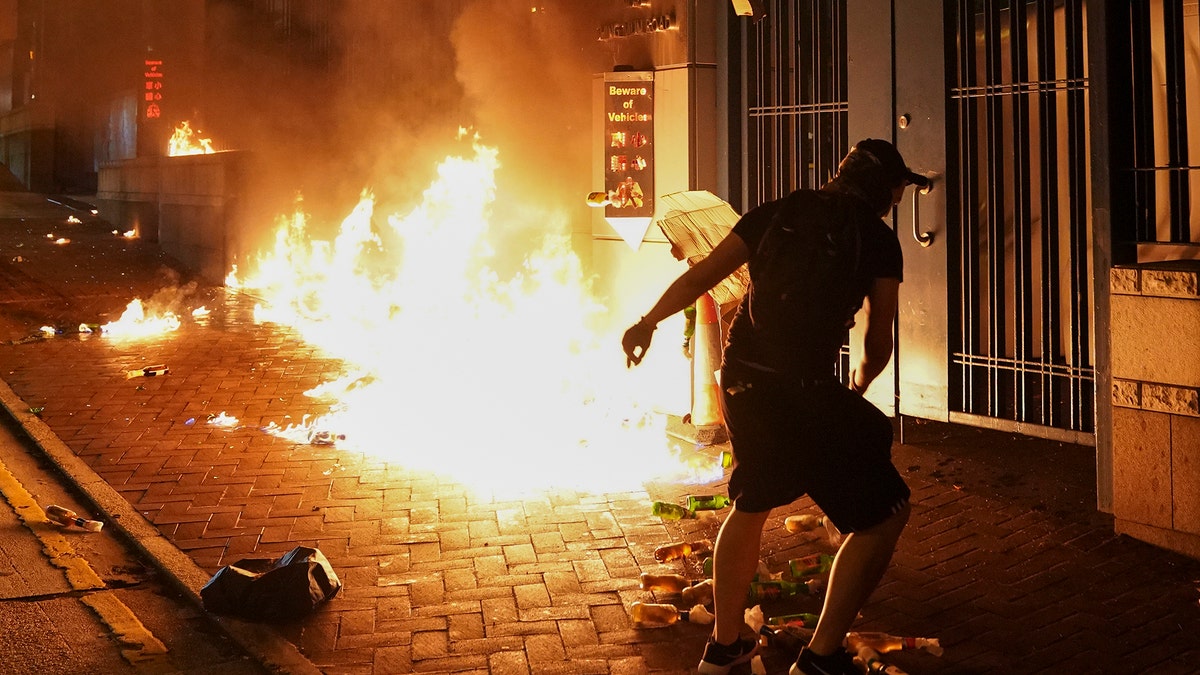 Protesters throw petrol bomb outside the Tsuen Wan police station in Hong Kong, Wednesday, Oct. 2, 2019. Holding up posters saying "Don't shoot our kids," Hong Kong residents and schoolmates of a teenage demonstrator shot at close range in the chest by a police officer rallied Wednesday to condemn police actions and demand accountability. (AP Photo/Vincent Thian)