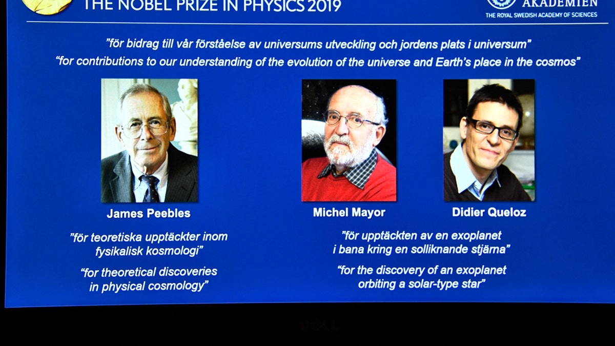 A screen displays the portraits of the laureates of the 2019 Nobel Prize in Physics, with left to right, James Peebles, Michel Mayor and Didier Queloz, during a news conference at the Royal Swedish Academy of Sciences in Stockholm, Sweden, on Tuesday Oct. 8, 2019. (Claudio Bresciani / TT via AP)