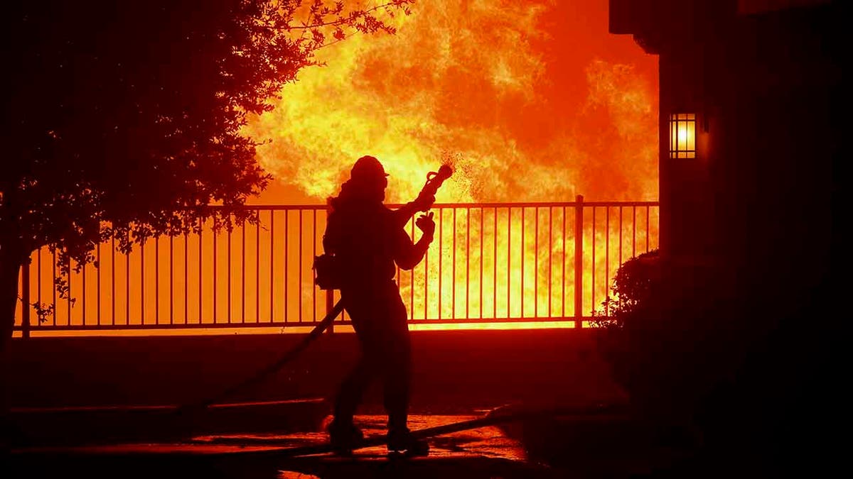 In this Thursday, Oct. 10, 2019 photo, a firefighter waits for water as the Saddleridge fire flares up near homes in Sylmar, Calif. (Associated Press)