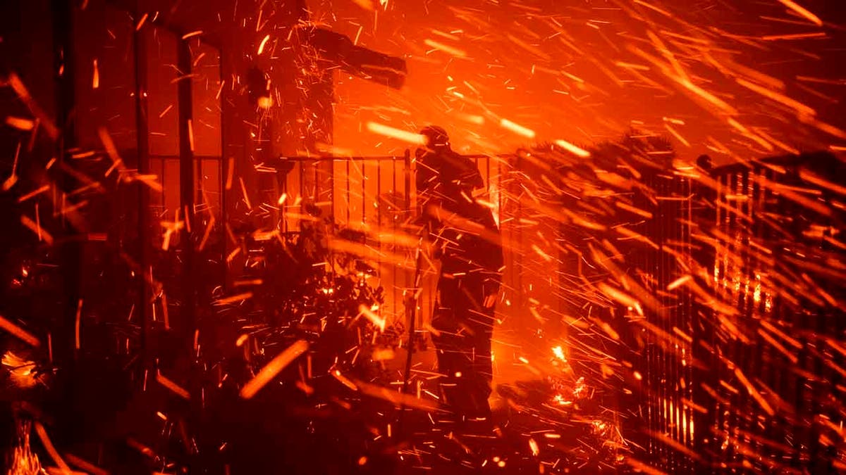 Jerry Rowe uses a garden hose to save his home on Beaufait Avenue from the Saddleridge fire in Granada Hills, Calif., Friday, Oct. 11, 2019. (AP Photo/Michael Owen Baker)