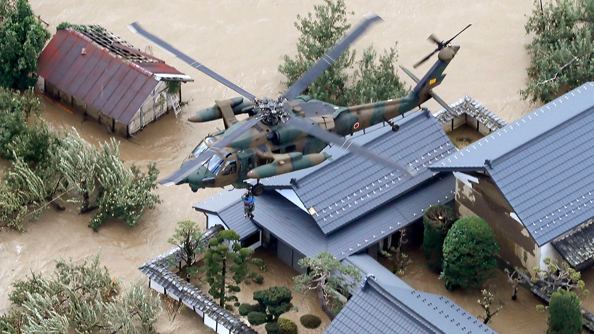A resident is rescued by a Japan Self-Defense Force helicopter as the house is submerged in muddy waters after an embankment of the Chikuma River broke because of Typhoon Hagibis, in Nagano, central Japan, Sunday, Oct. 13, 2019.