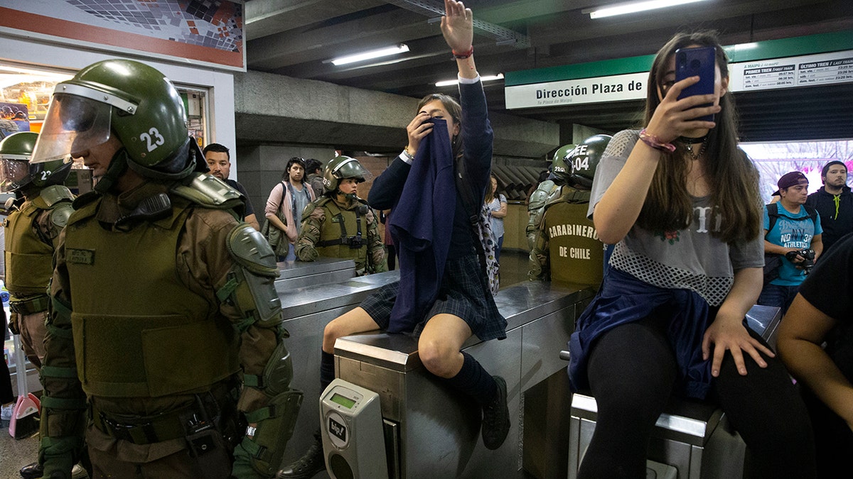 Chile's Carabineros stand next to students blocking the turnstile to the subway protesting against the rising cost of subway and bus fare, in Santiago, Friday, Oct. 18, 2019. (Associated Press)