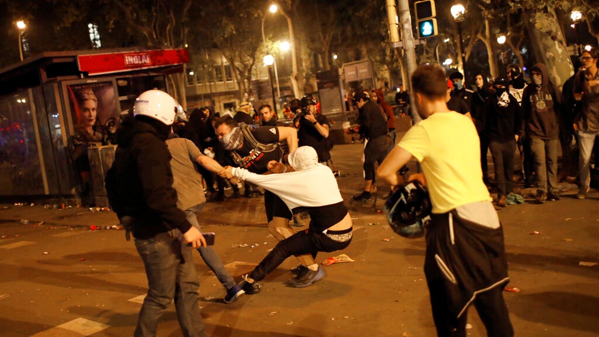 Pro-independence supporters scuffle with rioters trying to set up barricades on the street near a pro-independence demonstration in Barcelona, Spain, Saturday, Oct. 19, 2019. Radical separatists have clashed with police each night in Barcelona and other Catalan cities following huge peaceful protests of people angered by Monday's Supreme Court verdict that sentenced nine separatist leaders to prison. (AP Photo/Emilio Morenatti)