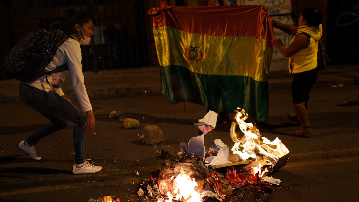 Supporters of opposition presidential candidate Carlos Mesa burn campaign posters of ruling party congressional candidates outside the Supreme Electoral Court where election ballots are being counted in La Paz, Bolivia, Monday, Oct. 21, 2019.