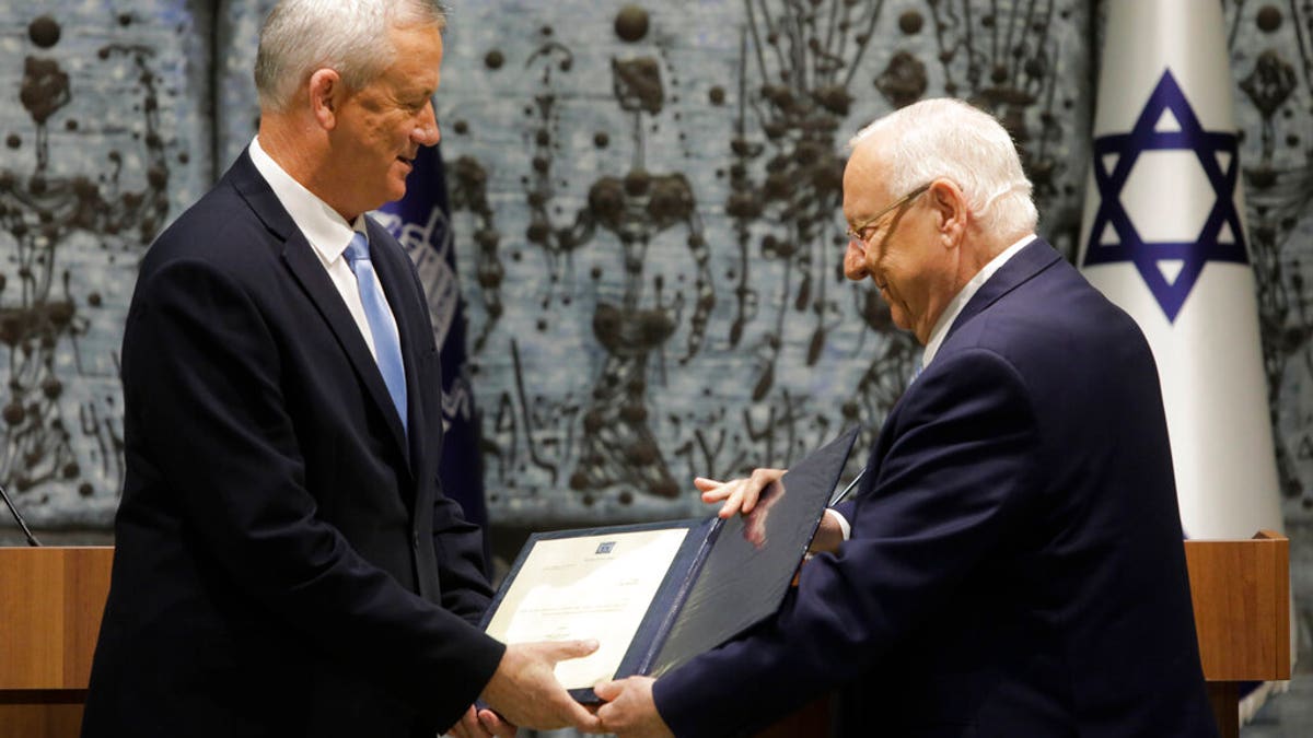 Israeli President Reuven Rivlin, right, hands a mandate to form new government to Blue and White Party leader Benny Gantz in Jerusalem, Wednesday, Oct. 23, 2019.