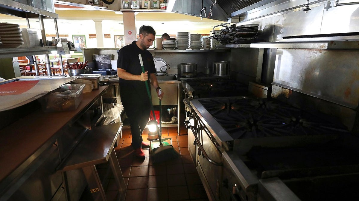 A power shutoff earlier this month leaves Salvador Espinosa with little to do but sweep up at Mary's Pizza Shack in Santa Rosa, Calif.
