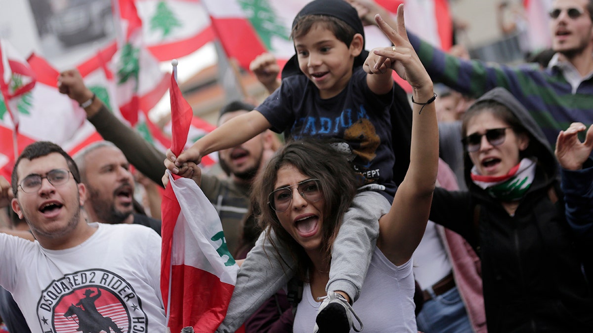 Anti-government protesters shout slogans against Lebanon's President Michel Aoun as they listen on a speaker while he addressees the nation during a protest in the town of Jal el-Dib north of Beirut, Lebanon, Thursday, Oct. 24, 2019. (AP Photo/Hassan Ammar)