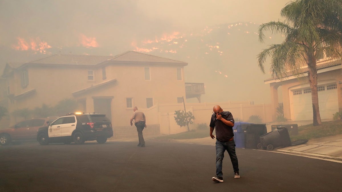 A resident covers his face as a wildfire approaches on Thursday in Santa Clarita, Calif. (AP Photo/Marcio Jose Sanchez)