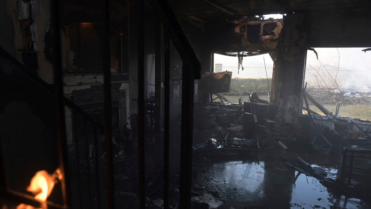 A burnt house lays flooded as leftover flames from the Tick Fire continue to burn in the Santa Clarita, Calif. on Thursday. (AP Photo/ Christian Monterrosa)