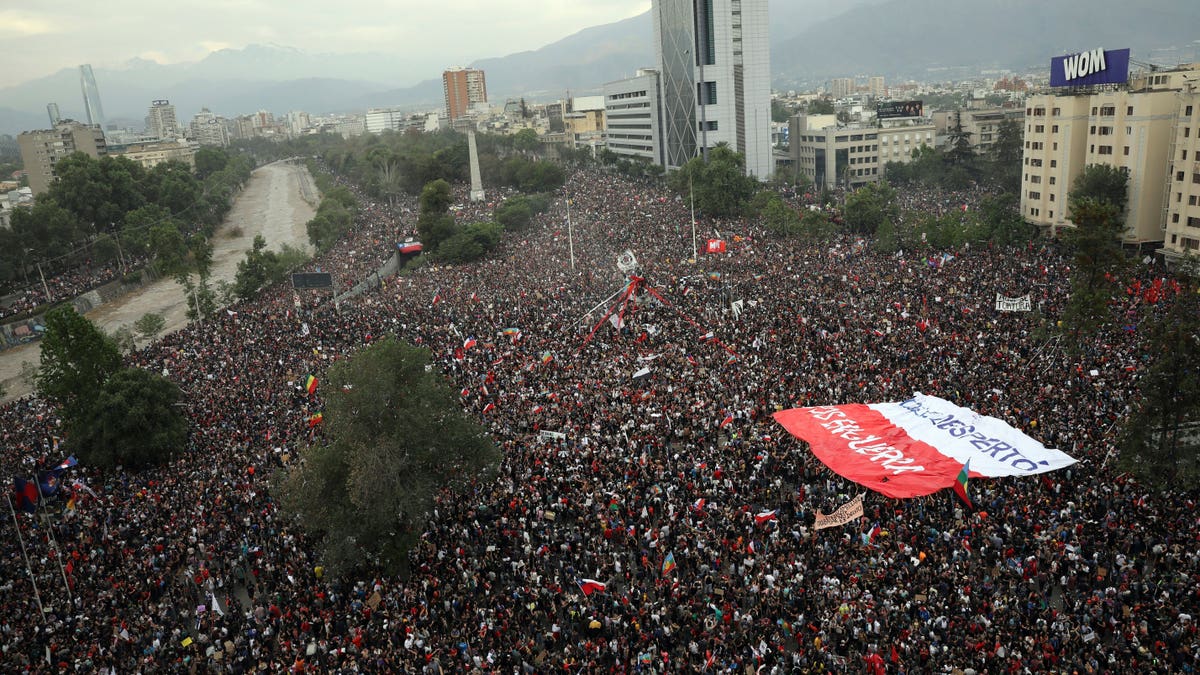 People gather during an anti-government protest in Santiago, Chile, Friday, Oct. 25, 2019. At least 19 people have died in the turmoil that has swept the South American nation. The unrest began as a protest over a 4-cent increase in subway fares and soon morphed into a larger movement over growing inequality in one of Latin America's wealthiest countries. (AP Photo/Rodrigo Abd)