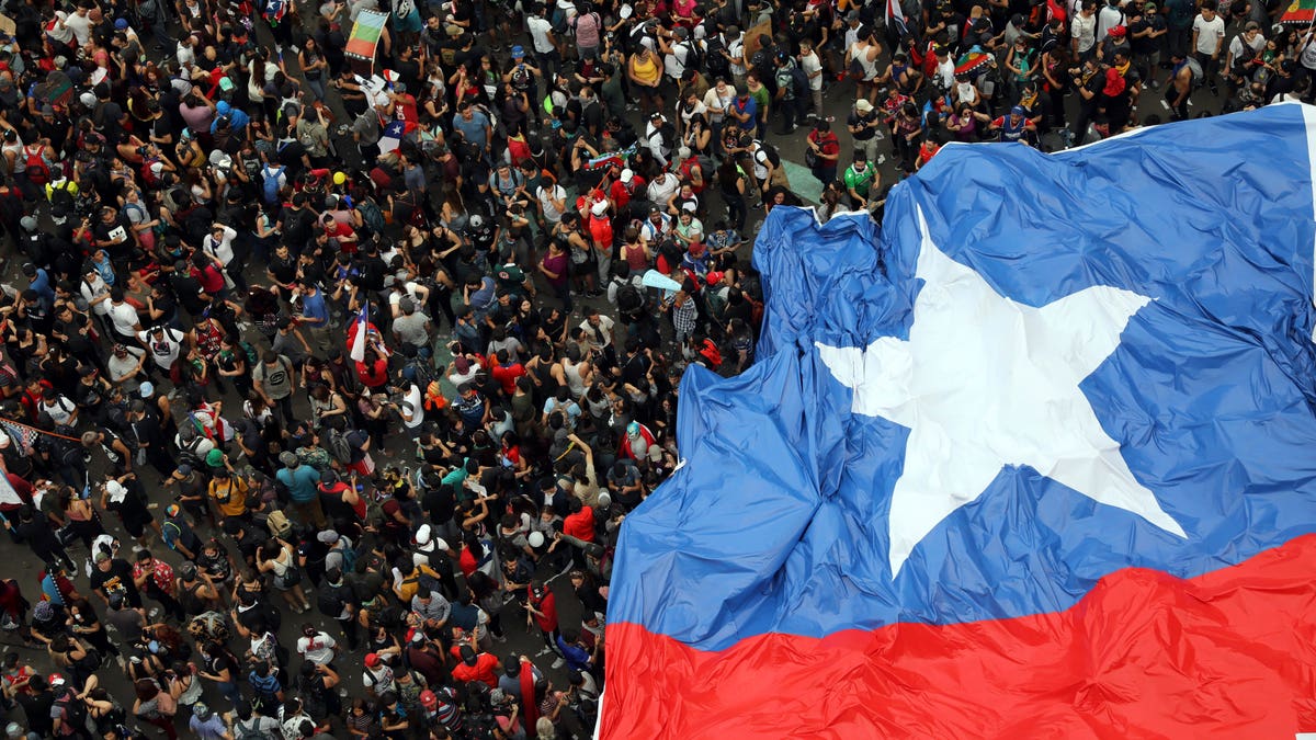 People gather during an anti-government protest in Santiago, Chile, Friday, Oct. 25, 2019. At least 19 people have died in the turmoil that has swept the South American nation. The unrest began as a protest over a 4-cent increase in subway fares and soon morphed into a larger movement over growing inequality in one of Latin America's wealthiest countries. (AP Photo/Rodrigo Abd)