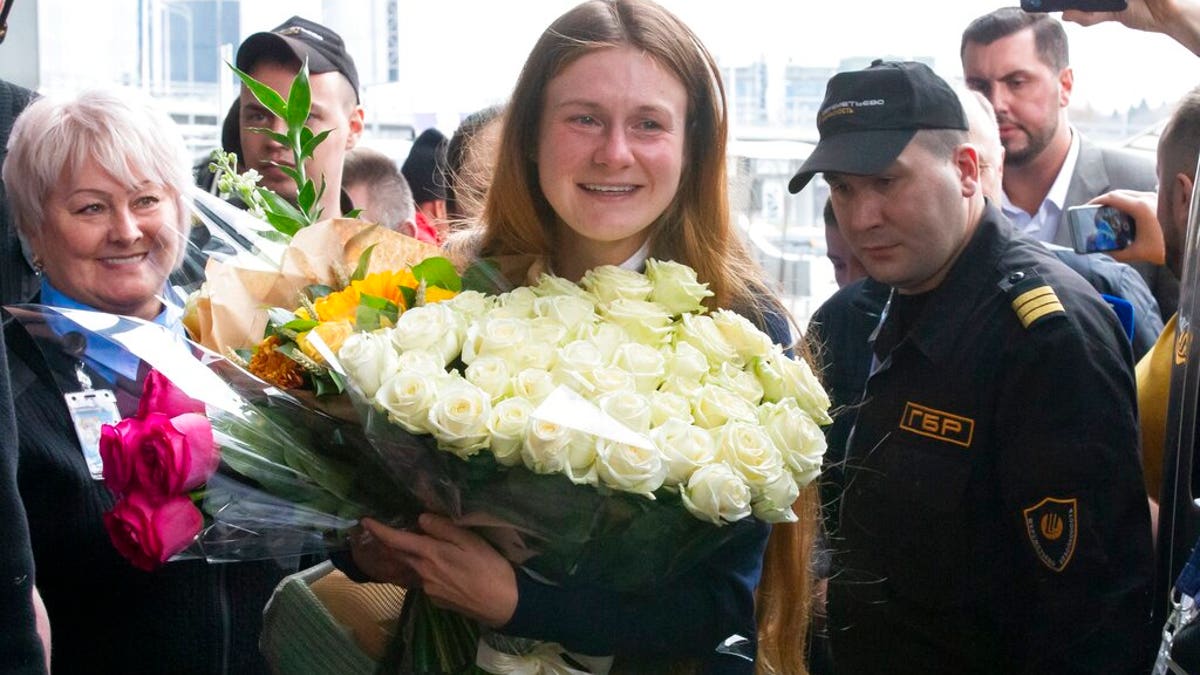 Russian agent Maria Butina, center, holds a bunch of flowers upon her arrival from the United States at Moscow International Airport Sheremetyevo outside Moscow.