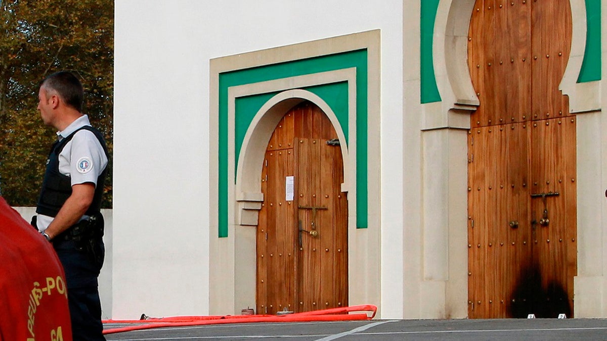 A police officer stands next to the entrance a mosque after an incident in Bayonne, southwestern France on Monday. French authorities say a suspect has been arrested for allegedly shooting and seriously injuring two elderly men who caught him trying to set fire to a mosque's door. (AP Photo/Str)