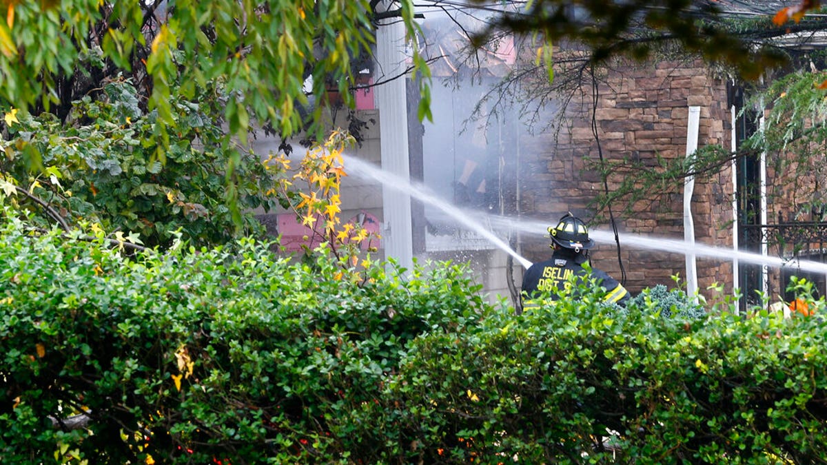 Woodbridge firefighters work to extinguish the scene of a plane crash in Colonia. (AP Photo/Noah K. Murray)