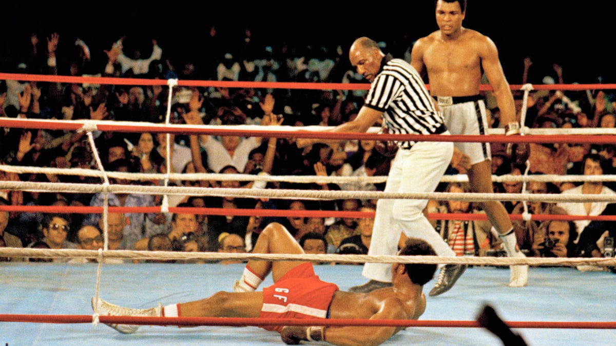 This is a Oct. 30, 1974 file photo of Muhammad Ali, right, as he stands back as referee Zack Clayton calls the count over opponent George Foreman, red shorts, in Kinshasa, Zaire. (AP Photo, File)