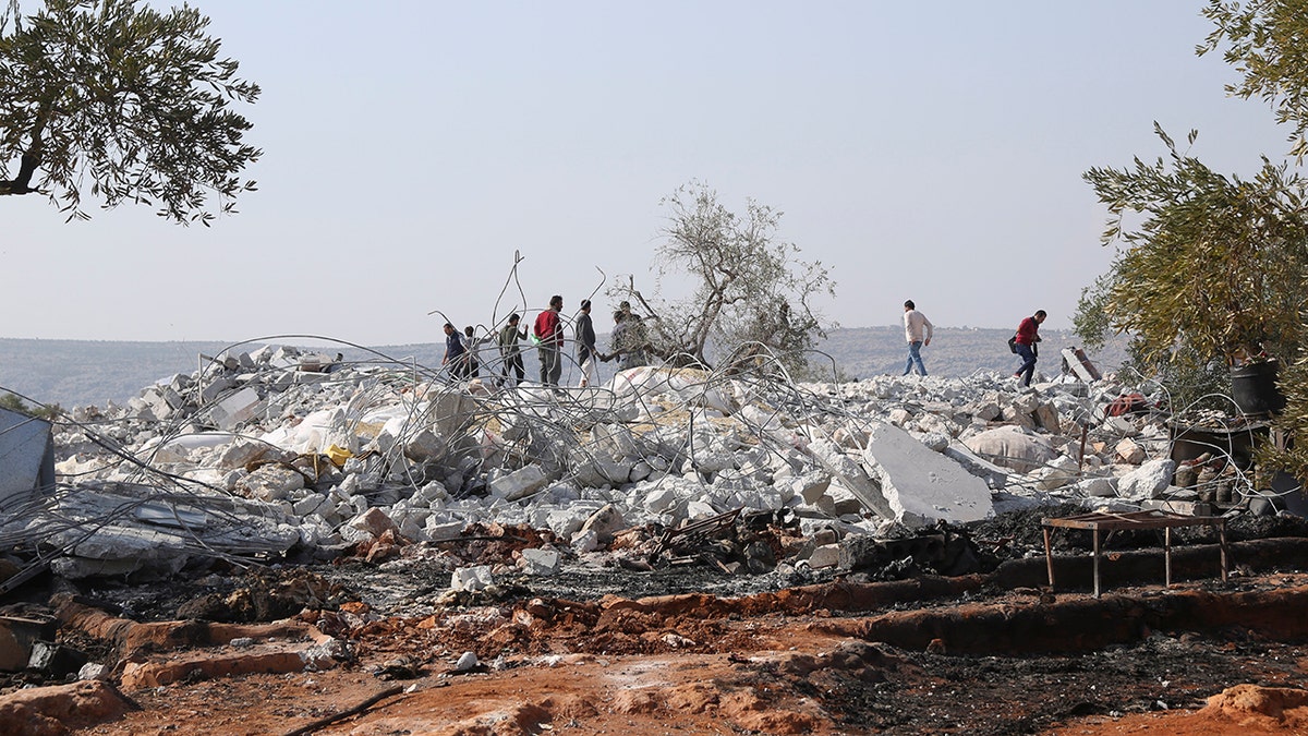 People look at destroyed houses near the village of Barisha, in Idlib province, Syria, Sunday, after an operation by the U.S. military which targeted Abu Bakr al-Baghdadi,