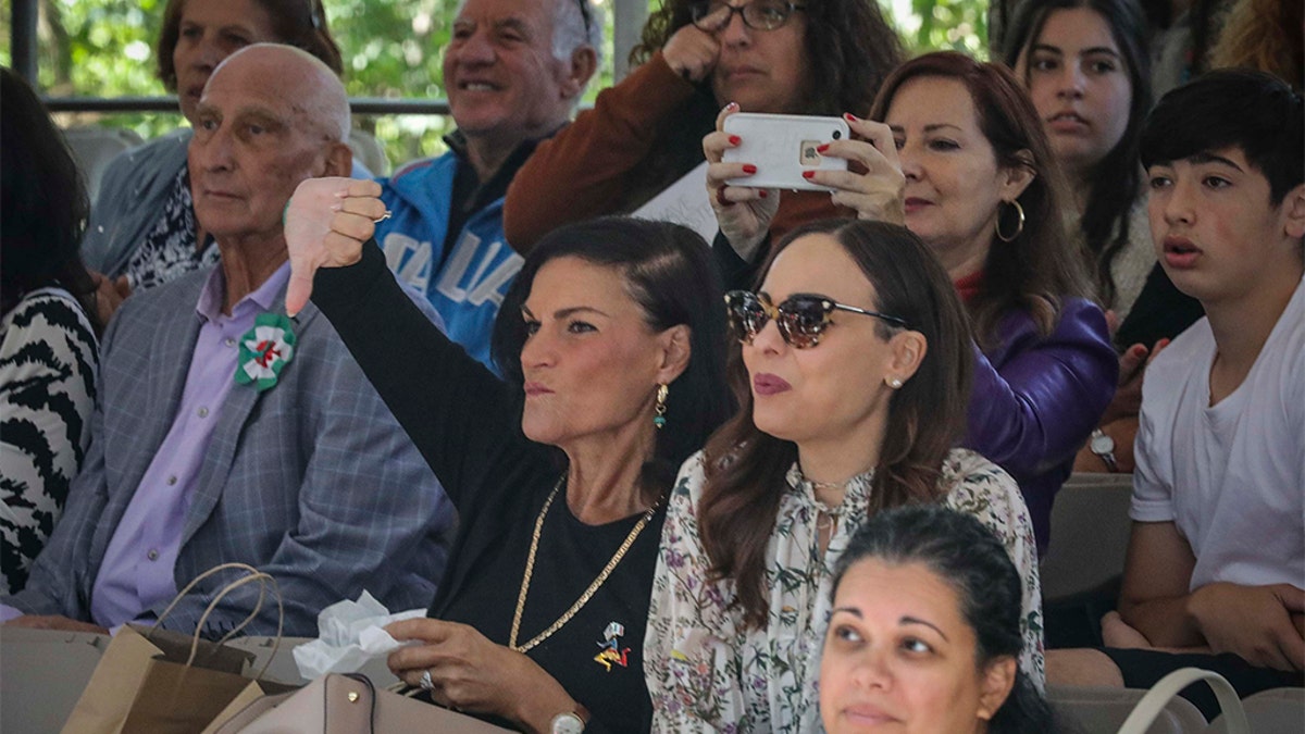 A viewer in the stands at the Columbus Day Parade gives a thumb down, while others boo and whistle as Mayor Bill de Blasio participates, Monday Oct. 14, 2019, in New York. (AP Photo/Bebeto Matthews)