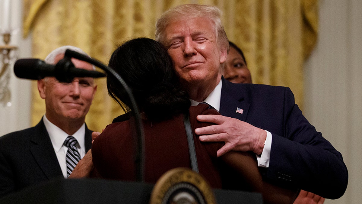 President Donald Trump embraces a woman on stage after she lead a prayer during the Young Black Leadership Summit at the White House in Washington, Friday, Oct. 4, 2019. At left is Vice President Mike Pence. (AP Photo/Carolyn Kaster)