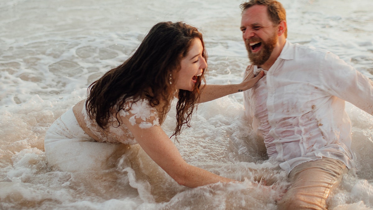 A Texas couple's beachside wedding photos didn't turn out quite the way they expected after an ocean tide caused them to tumble, ruining the bride's dress in the process.