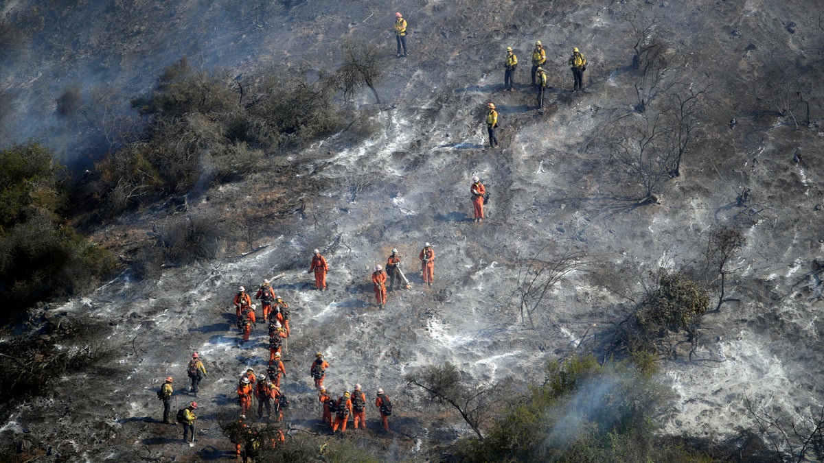 Hand crews work a wildfire-damaged hillside as the Getty fire burns on Mandeville Canyon, Oct. 28, 2019, in Los Angeles.