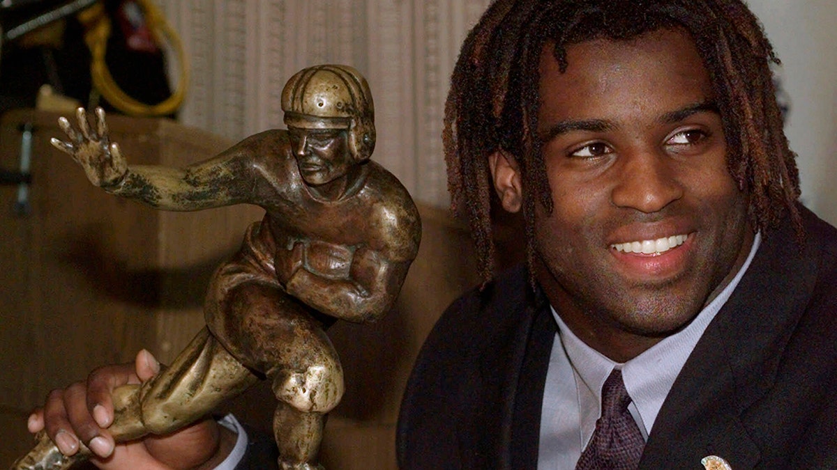 FILE - In this Dec. 12, 1998, file photo, Texas tailback Ricky Williams poses with the Heisman trophy at the Downtown Athletic Club in New York. Brian Hobbs remembers getting a call in 2014 to let him know retired football star Ricky Williams was interested in selling his Heisman Trophy. (AP Photo/Suzanne Plunkett, File)