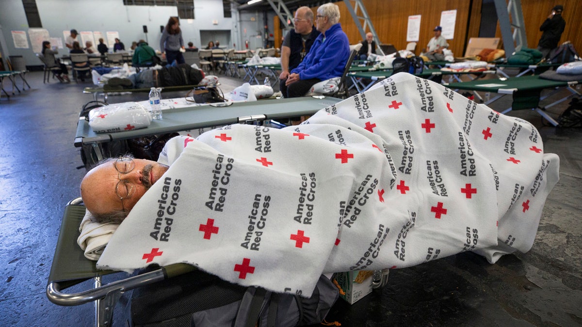In this Sunday, Oct. 27, 2019, photo, Jim Keefauver rests at a Red Cross shelter set up for wildfire evacuees at the Sonoma County Fairgrounds in Santa Rosa, Calif., after evacuating his Santa Rosa home in the morning.