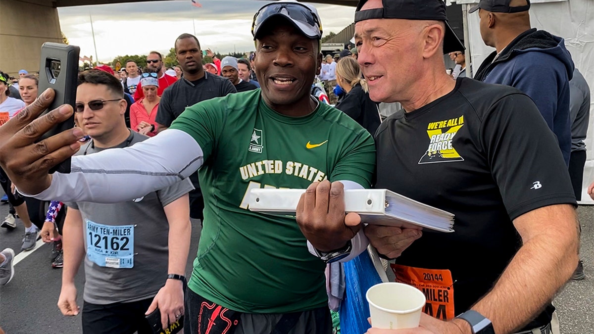 Moss takes a selfie with Lt. Gen. Charles Luckey, commanding general of the U.S. Army Reserve, while showing him a binder representing the fallen veterans of the Vietnam War during the Army Ten Miler in Washington, D.C., on Oct. 13. (U.S. Army Reserve photo by Staff Sgt. Felix Fimbres)