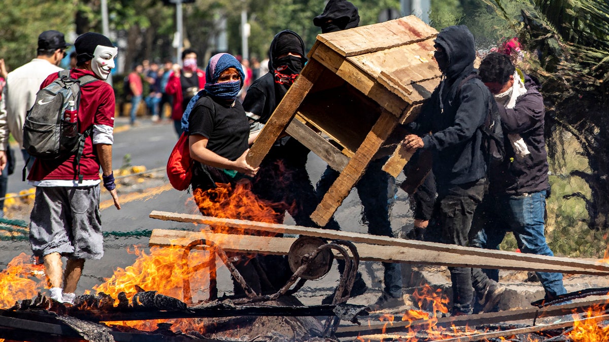 Demonstrators build a burning barricade during a protest in Santiago, Chile, Saturday, Oct. 19, 2019.