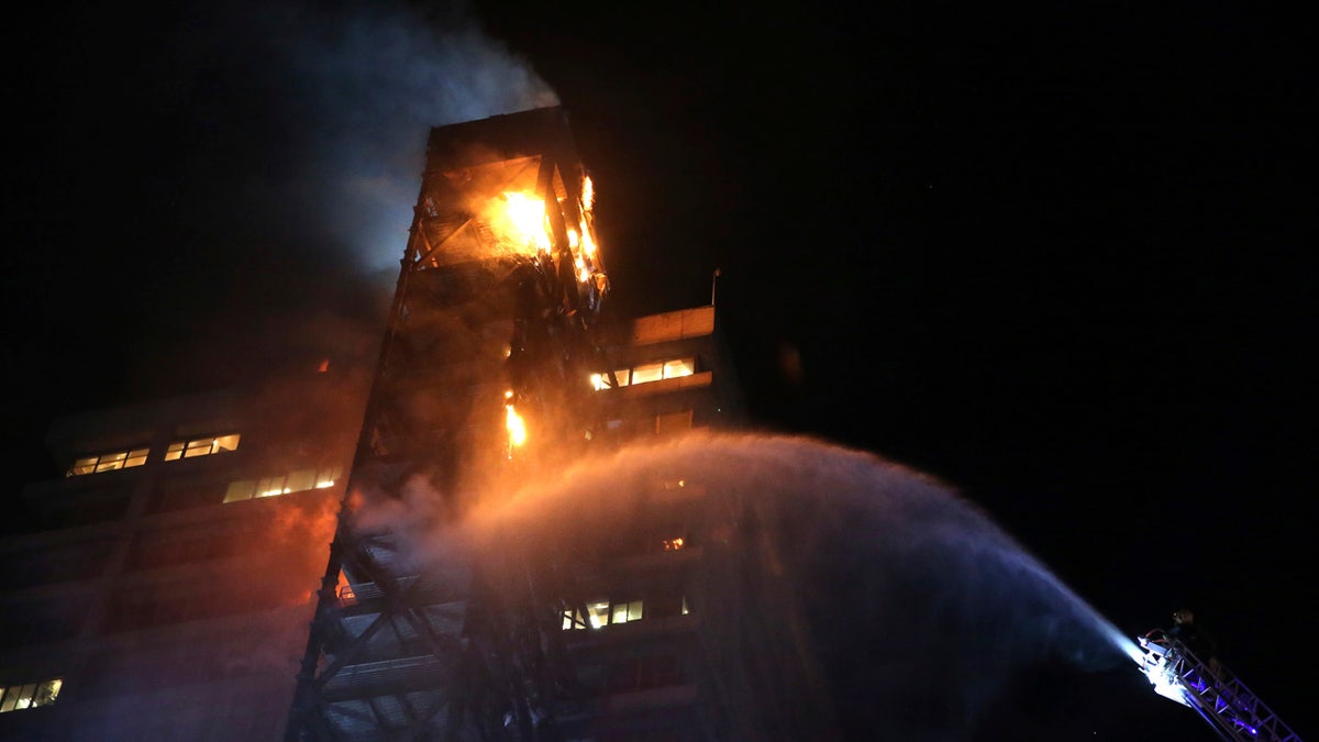 Firefighters work to put out the flames rising from the Enel Energy Europe building set on fire by protesters against the rising cost of subway and bus fares, in Santiago, Friday, Oct. 18, 2019.