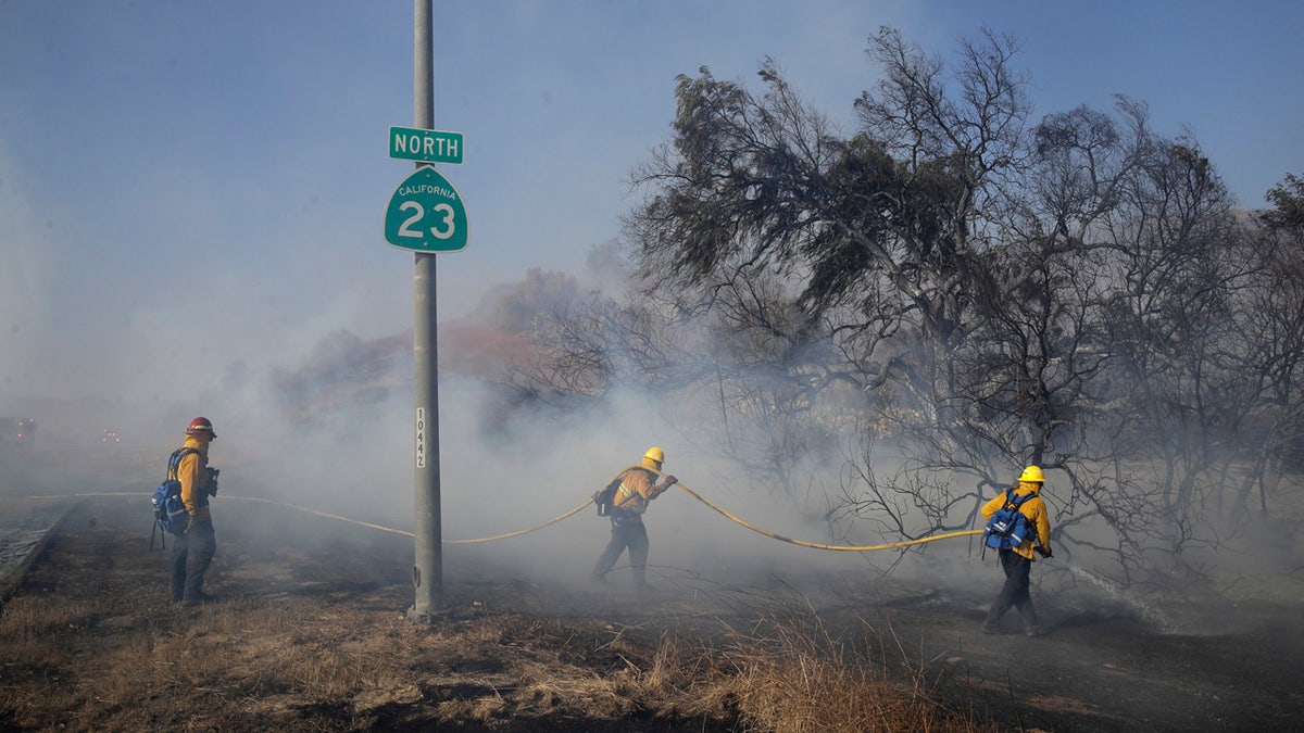 Firefighters put out hot spots along Highway 23, closed to traffic due to the Easy Fire, Wednesday, Oct. 30, 2019, in Simi Valley, Calif.