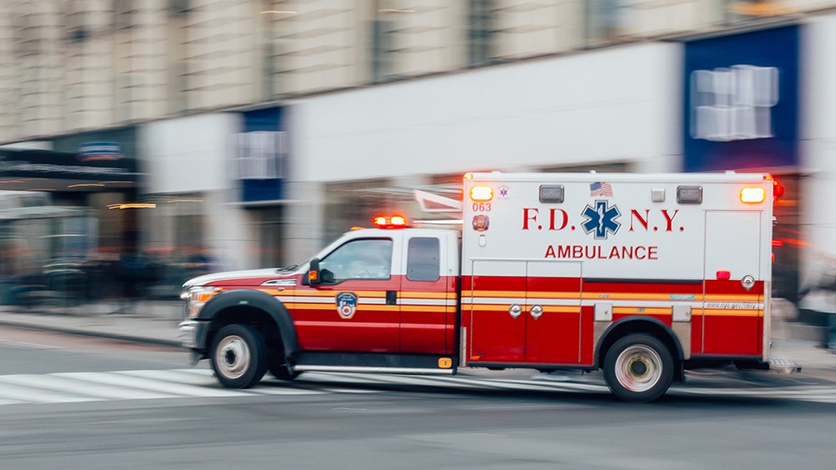 FDNY Ambulance flashing lights siren blasting speed through midtown rush hour traffic in Manhattan.