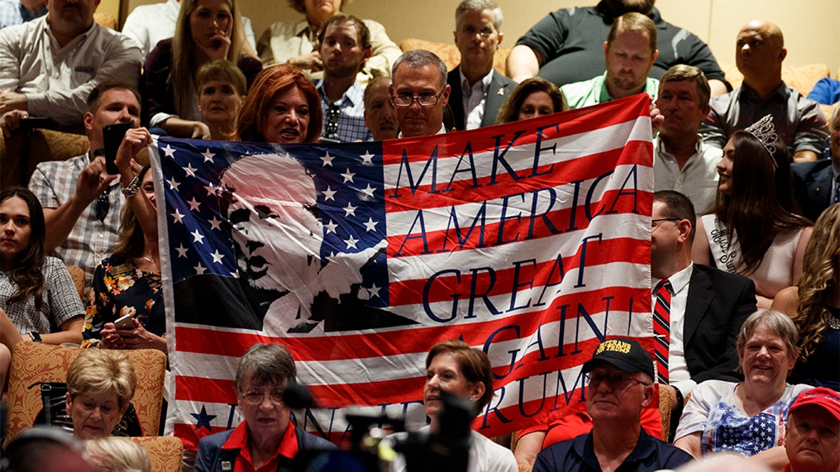 Supporters of President Donald Trump hold a flag before he arrives to deliver remarks on Medicare at the Sharon L. Morse Performing Arts Center, Thursday, Oct. 3, 2019, in The Villages, Fla. (AP Photo/Evan Vucci)