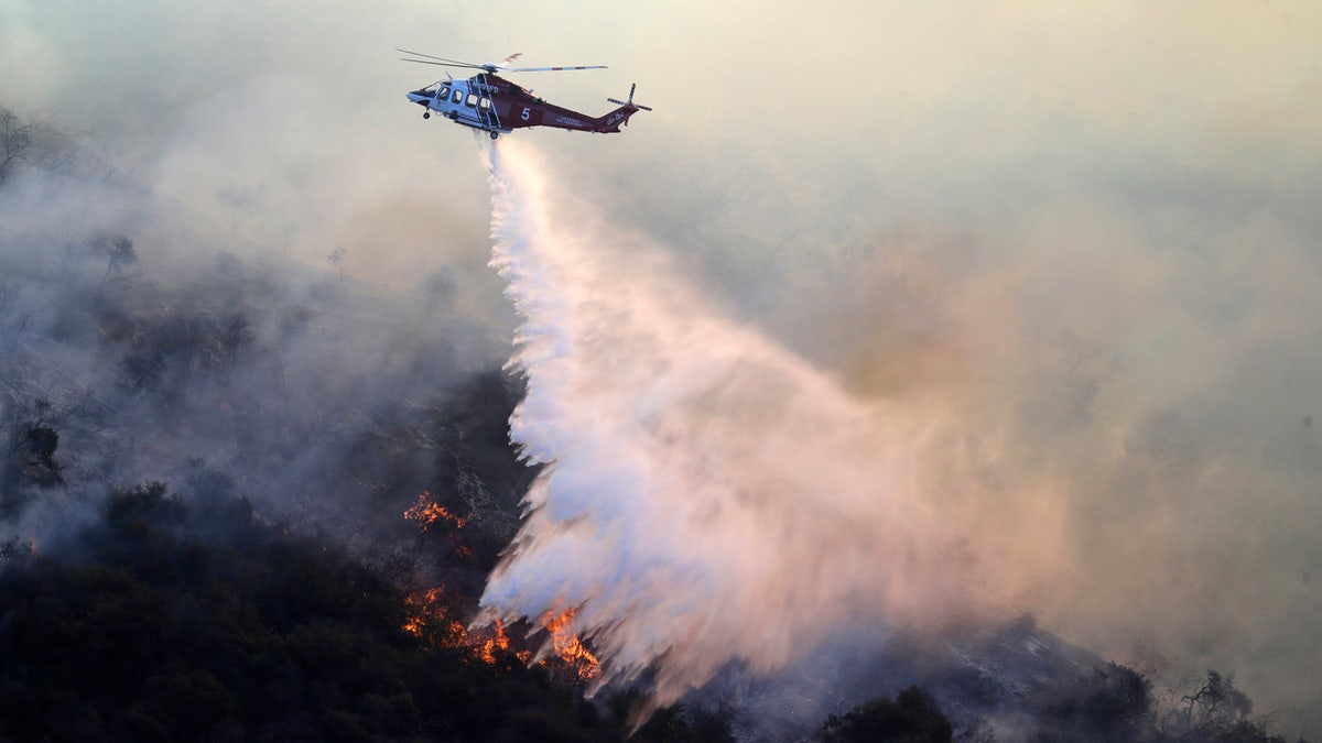 A helicopter drops water as the Getty fire burns on Mandeville Canyon Monday, Oct. 28, 2019, in Los Angeles.